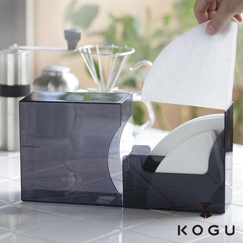 KOGU 珈琲考具推出的日製分隔式咖啡濾紙收納盒，展示透黑設計，左側為較大的濾紙盒，右側則裝有咖啡濾紙，手部正在拿取一張濾紙。