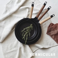 黑釉琺瑯鑄鐵平底深鍋，鍋內有迷迭香，鍋柄為木質，風格簡約。