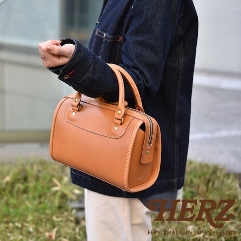 職人手作皮革迷你波士頓包，採用天然牛皮材質，呈現溫潤的焦糖色澤，配有圓潤的提把與精緻的縫線裝飾，簡約而經典的設計。
