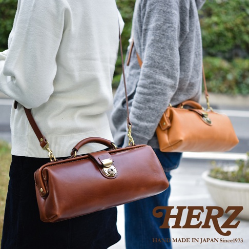 日本HERZ職人手作皮革橫長形杜勒斯單肩包，兩個側背包，一個淺棕色，一個深棕色，在戶外拍攝
