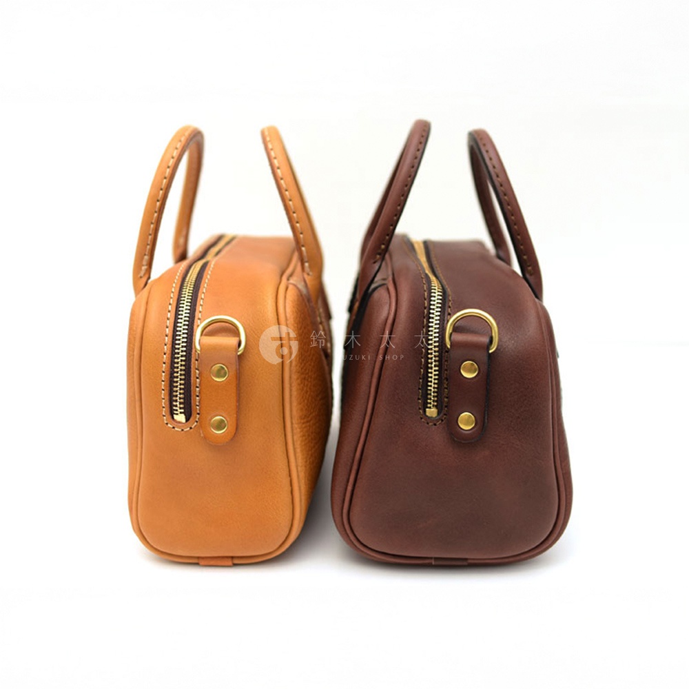 日本HERZ職人手作皮革兩用迷你波士頓包，從側面展示了焦糖色與深棕色兩款包包，皆配有金色拉鍊和圓形金屬提把。