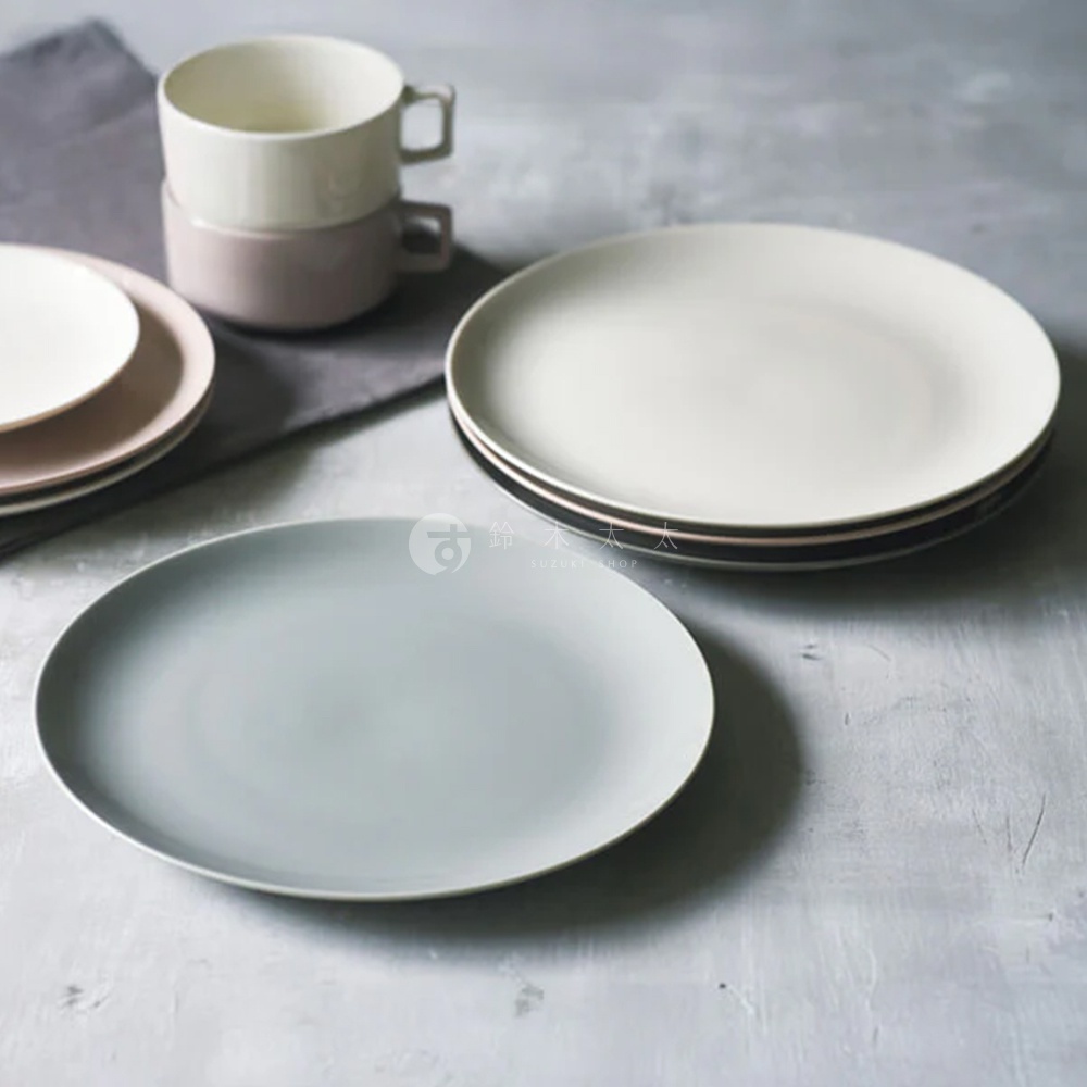 一組日式美濃燒圓形餐盤，包含淺灰色、白色及粉色盤子，與兩個疊放的淺粉色及白色馬克杯，皆為陶瓷材質。