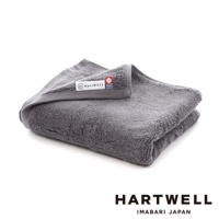 一張對折的灰色今治純棉毛巾，毛圈蓬鬆，質感厚實，帶有「HartWELL」品牌標籤。