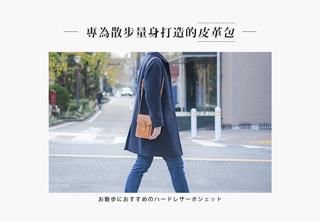 一名身穿深藍色大衣和牛仔褲的女性，側身展示一個 tan 色皮革斜背包，包款為長方形，有翻蓋和金屬扣。