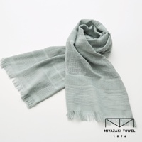 一條淺灰綠色的今治匹馬棉圍巾，帶有不同寬度的條紋織紋和流蘇邊緣，圍巾部分纏繞成圈。