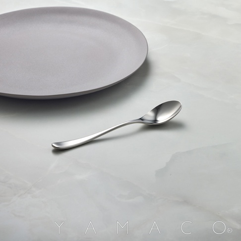 霧面不鏽鋼點心匙放在灰色盤子旁邊，背景為大理石紋桌面