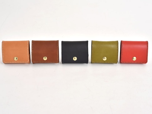 五款職人手作皮革箱型收納零錢包，顏色包含淺棕、深棕、黑色、橄欖綠及紅色，均採用皮革材質，正面配有金色按扣。