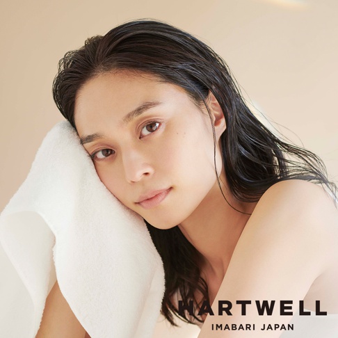 一名女子臉頰輕柔地貼著一條白色柔軟的今治浴巾。