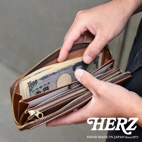 職人手作皮革Organ拉鍊長夾，棕色皮革，拉鍊開闔，內部裝有日圓鈔票與信用卡。