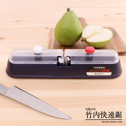 竹內式金剛鑽磨刀器，深藍色塑膠外殼，透明頂蓋，設有白色和紅色調節鈕。磨刀器內有金剛鑽磨輪。背景為木質桌面，有兩顆綠色梨子和一把鋼製刀具。