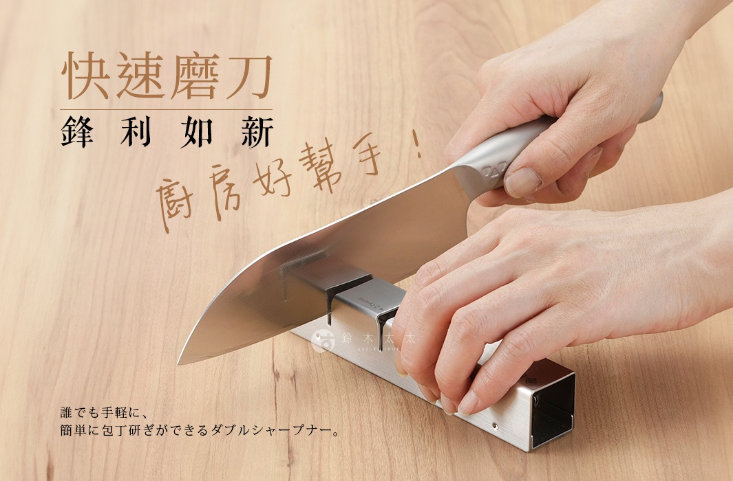 一雙手正握著銀色不鏽鋼刀柄，將刀刃置於 ESSYO 越匠系列可拆式不鏽鋼雙滾輪磨刀器上，磨刀器主體為銀色不鏽鋼材質，呈長方形。