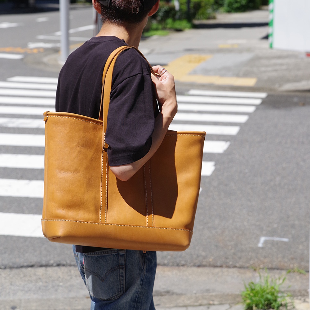 職人手作皮革經典托特包，淺棕色牛皮材質，簡約設計，雙提把，車縫線清晰，適合日常攜帶。