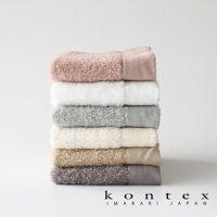 PRIMAVERA 超細纖純棉毛巾堆疊展示，包含粉色、白色、淺灰綠、米白、淺褐、深灰紫共六色。毛巾質地蓬鬆柔軟，每條毛巾皆有素面設計及部分區域的織紋變化。