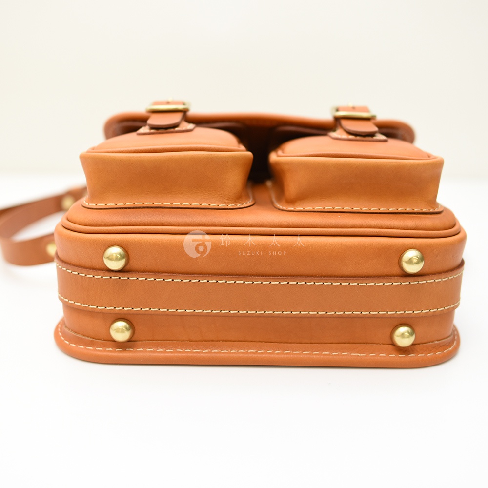 日本HERZ職人手作皮革經典雙扣郵差包，近距離拍攝，呈現焦糖色皮革的光澤與精緻縫線。