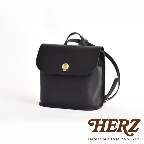 黑色皮革翻蓋迷你後背包，配有金色轉鎖，簡約設計，適合日常使用。