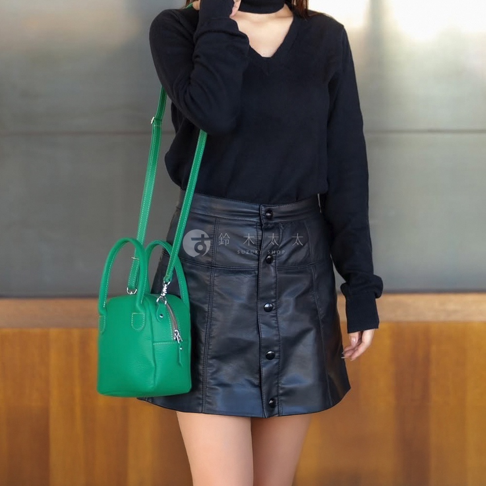 綠色皮革手提包，配有單肩斜挎帶，頂部有拉鍊開合和雙提手。