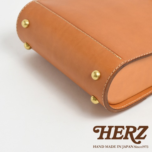 職人手作皮革杜勒斯商務後背包 BJ-10，展示了棕色皮革的細緻質感，搭配黃銅鉚釘和白色縫線，展現簡約的商務風格。