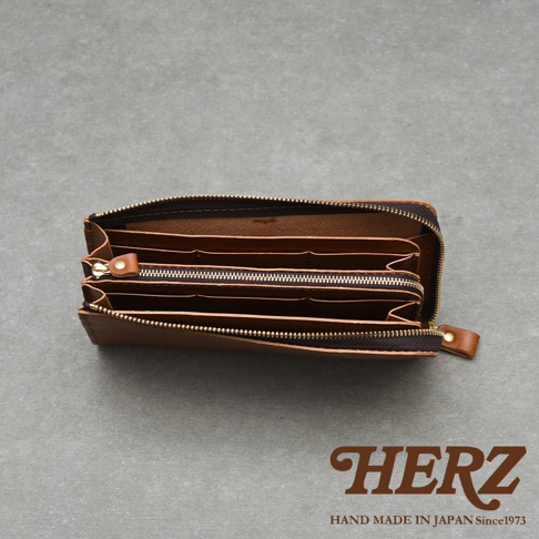 HERZ 品牌標誌，以及 HAND MADE IN JAPAN Since1973 字樣，搭配打開的棕色皮革長夾內部結構。