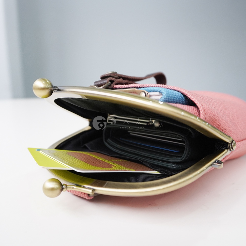 粉色帆布腰掛口金包，打開的包內有卡片及零錢包，金屬扣環精緻，包上有品牌標誌。