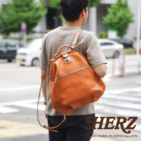 職人手作皮革輕旅行後背包，採用溫暖的棕褐色皮革，搭配金色拉鍊和金屬扣環。包款設計簡潔，容量適中，適合日常或短途旅行攜帶。