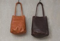 兩款皮革托特包，一款為棕褐色，另一款為深棕色，皆為手提肩背款式，材質為皮革，具有抽繩開合設計。