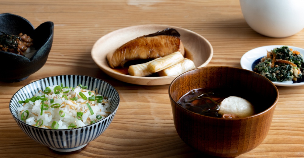 日式餐點，包含一碗淋有醬汁的烤魚佐竹筍，一碗白飯撒有蔥花與吻仔魚，一碗湯品，以及一小碟蔬菜。