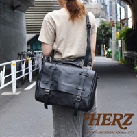 黑色皮革復古郵差包，配有雙搭扣和可調節肩帶，由職人手工製作。