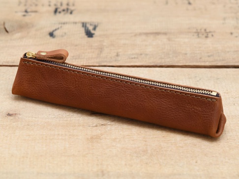 職人手作皮革Organ三角收納筆袋，採用咖啡棕色皮革製成，搭配金色拉鍊和皮革拉頭，設計簡約，適合收納文具。