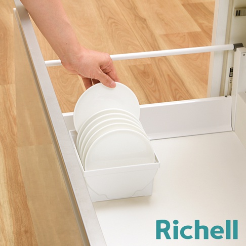 一個人正將白色盤子放入抽屜式餐盤收納架，架子內已堆疊數個白色盤子。