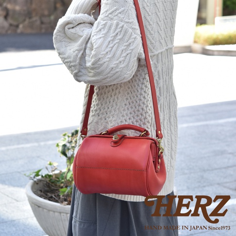 紅色職人手作皮革口金醫生單肩包，包身圓潤，配有頂部提把及可拆卸斜背帶，細膩縫線與金屬釦件增添質感。