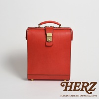 職人手作紅色皮革杜勒斯商務後背包，配有金色鎖扣和提把，底部有四個金色腳釘。