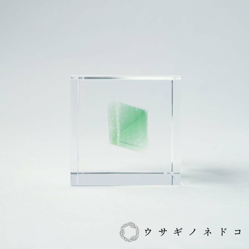方形透明壓克力塊中，封存著一塊綠色的螢石礦石，呈現晶瑩剔透的質感。