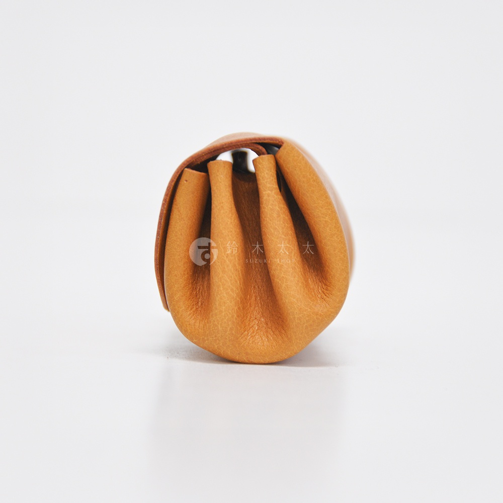 職人手作皮革三層收納零錢包，呈現自然棕色皮革，包身有皺褶設計，可見細緻紋理。