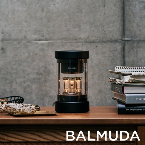 The Speaker 無線揚聲器，黑色圓柱形機身，透明玻璃外殼內有三個發光的真空管。