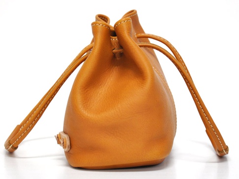 職人手作皮革可調式兩用托特包 (Q-14)，呈現圓潤的束口水桶包造型，以溫暖的橘棕色皮革製作，搭配米白色車線，質感細膩。皮革上可見自然的紋理與束繩設計。