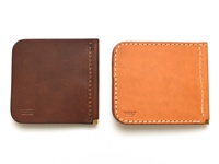 兩款職人手作皮革短夾，一款為深棕色，另一款為淺棕色。兩款皆為橫式對折設計，使用皮革材質，邊緣有縫線裝飾。