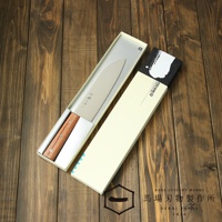 [堺一次] 不鏽鋼三德刀，刀刃為銀色不鏽鋼材質，木柄為茶色，刀身有日文刻字，產品置於銀色內襯的紙盒中，旁有一淺米色紙盒。