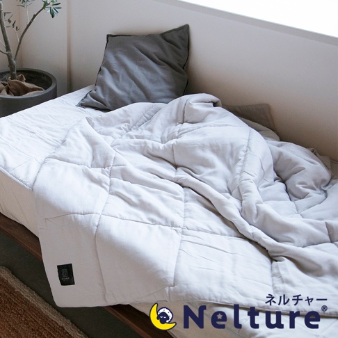 Nemulia 五層散熱涼感單人被，淺灰色，材質柔軟，表面有菱形格紋縫線。被子鋪在床上，旁有一張灰色枕頭和一盆綠植，角落處有品牌標誌。