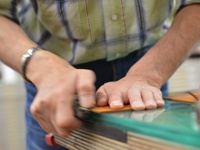 職人雙手正在細緻打磨植鞣皮革A5筆記本書套，展現皮革自然紋理與溫潤色澤，細節處精緻處理。