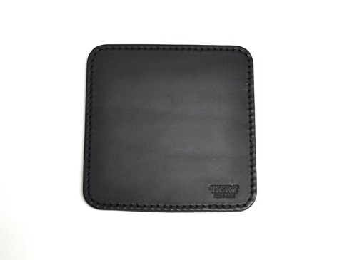 職人手作黑色皮革印章墊板，方形設計，邊緣縫線整齊，右下角印有「HERZ」品牌標誌。