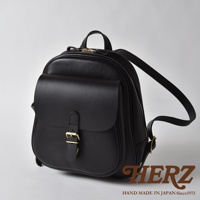 黑色皮革迷你後背包，設有立體前袋、黃銅釦環及拉鍊，背帶可調節，整體風格簡潔。