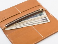 職人手作皮革簡約輕薄扁長夾，原色皮革材質，搭配白色車縫線，內部可見拉鍊零錢袋及多張日圓鈔票。