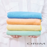 HARUKA 今治耐用絢彩拼接毛巾，堆疊展示四種顏色：藍色、橘色、黃色和綠色，毛巾質地柔軟，觸感舒適。