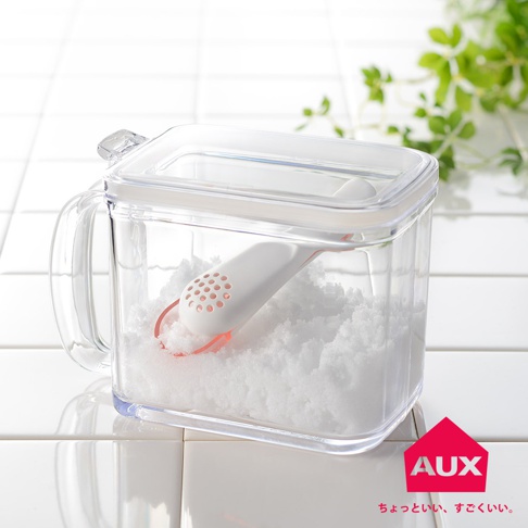 透明塑膠製成的手柄式調味品儲存盒，內含白色調味品和一個帶有粉紅色邊緣和圓孔的白色湯匙。