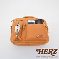 職人手作皮革兩用多功能收納單肩包，淺棕色，展示包內裝有手機、電池、充電線和卡夾，具備多個拉鍊和開放式口袋。