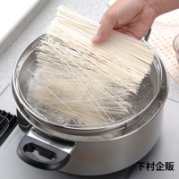 手持一束細長麵條，準備放入裝有滾水的不鏽鋼深型料理濾網籃中。濾網籃置於鍋內，網孔清晰可見。