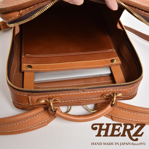 職人手作皮革商務電腦後背包 R-25，展示內部隔層，可容納筆記型電腦，採用 tan 色皮革，搭配白色縫線與黃銅五金配件。