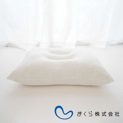 白色無敵軟枕，表面柔軟，中央有凹陷設計，材質看起來像絨布，背景為白色窗簾。