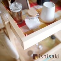 淺木色木藝收納推車，頂層有兩個玻璃儲物罐，一個裝有咖啡粉，另一個裝有白色顆粒物。旁邊還有一個白色杯子和一塊格子布。