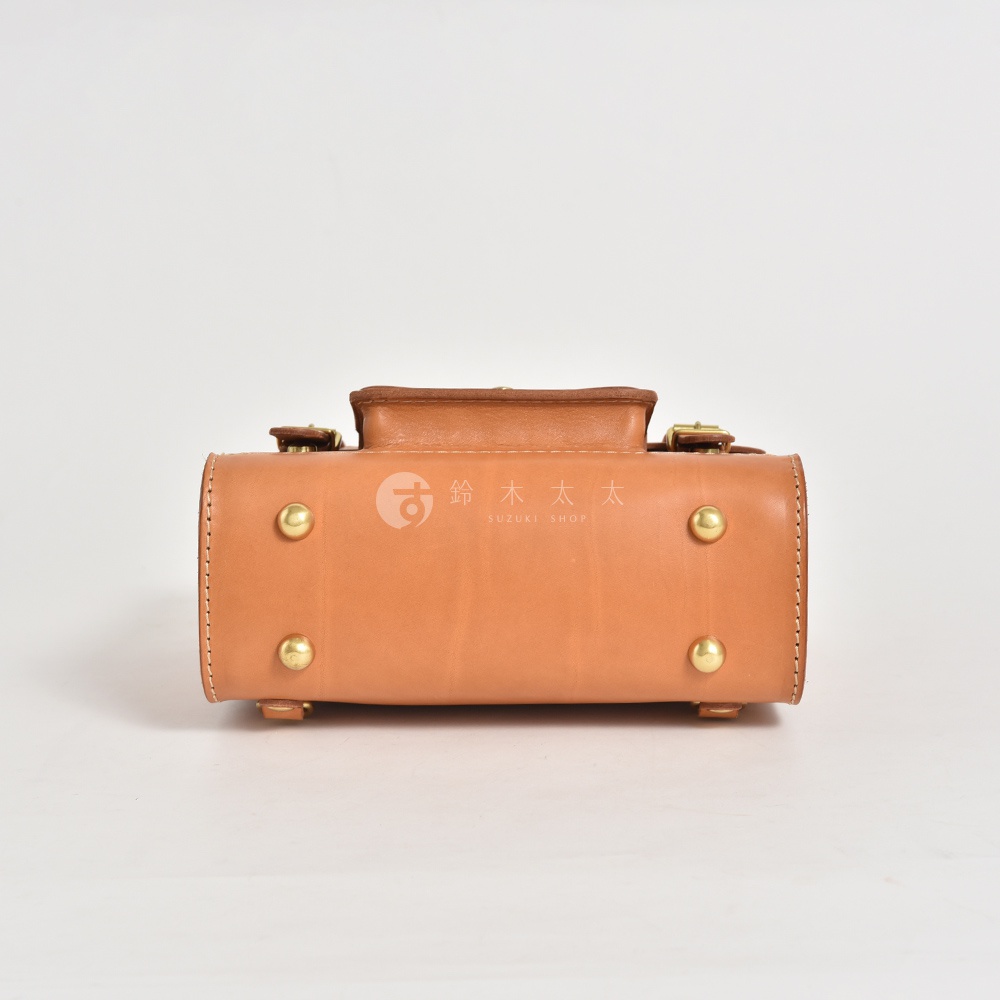 職人手作皮革學院風三用迷你後背包，採用天然皮革材質，呈現溫潤的棕褐色調。包款設有金屬腳釘裝飾，搭配簡潔的學院風格設計，適合日常攜帶。